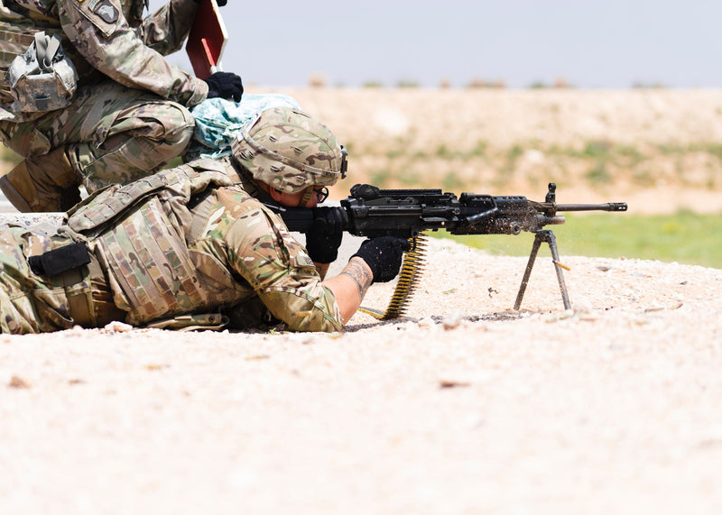 Soldier shooting firearm at AR500 steel target outdoors.