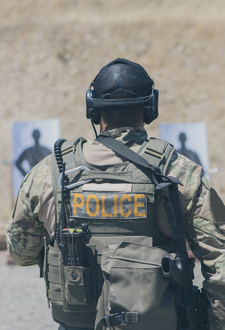 A person in a police combat uniform at a shooting range.